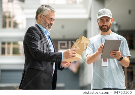 Bearded elegant businessman taking the box from a courrier 94763160