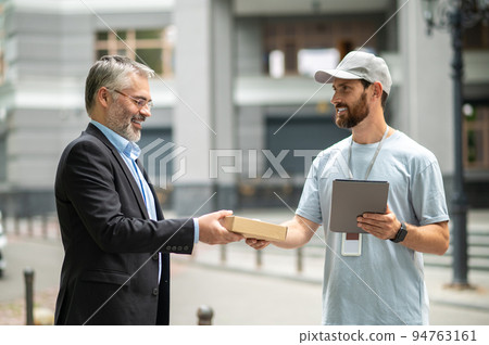 Bearded elegant businessman taking the box from a courrier 94763161