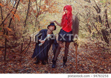 Beautiful witch and dwarf in the autumn forest. 94763258