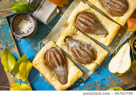 Homemade Cake Puff Pastry with Pear and Stuffed with Nut Cream a blue wooden table. Top view flat lay background. Homemade Cake Puff Pastry with Pear and Stuffed with Nut Cream a blue wooden table. Top view flat lay background. 94763799