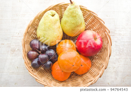 Basket with assorted autumn fruits (persimmons, pears, grapes, apples) 94764543