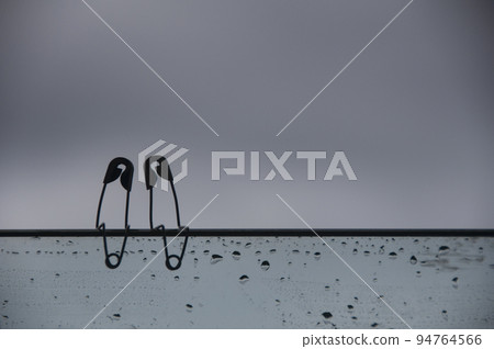 Safety pin couple sitting on glass wall with customizable space for text and ideas. Love and romance concept. 94764566