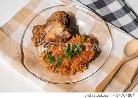 Bowl of east African Jollof Rice garnished with pieces of roasted chicken 94764804