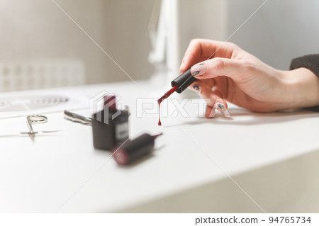 Nail polish drips from the brush to the table in the nail salon. Nail polish drips from the brush to the table in the nail salon. 94765734