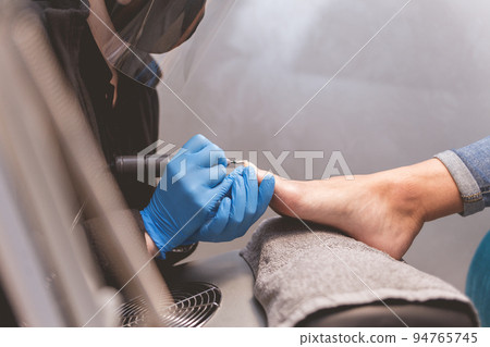 Pedicure master polishes nails with nail file drill before applying varnish side view. 94765745