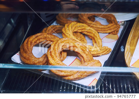 Sweet baked churros pretzel with cinnamon and caramel on counter in street cafe, closeup 94765777