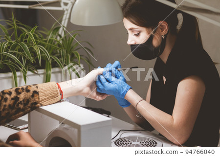 Manicurist cleans cuticles for client. 94766040