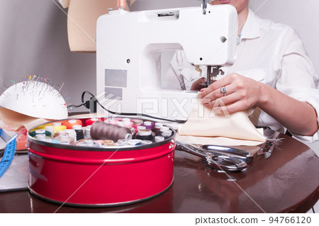 close up shot of a woman's hands, who is engaged in sewing in the home. close up shot of a woman's hands, who is engaged in sewing in the home. 94766120