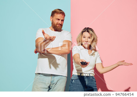 Expressive young people, man and woman, husband and wife spending time together isolated over blue and pink background. 94766454