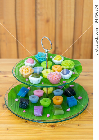 Varieties traditional colorful Thai desserts set; NamDokMai (steaming flour), PiekPoon (black custard), LeumKluen (coconut custard & steaming bean), KanomChan (layer pudding cake) 94766574