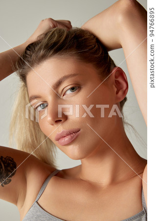 Close-up portrait of beautiful woman with nude makeup isolated over grey background. Perfect brows and lips Close-up portrait of beautiful woman with nude makeup isolated over grey background. Perfect brows and lips 94766895