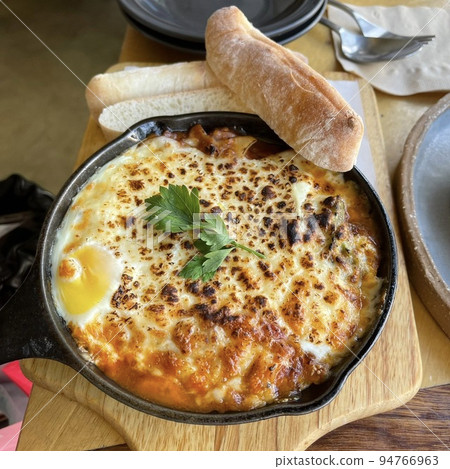 Meat sauce and cheese grilled on a hot iron plate with bread 94766963