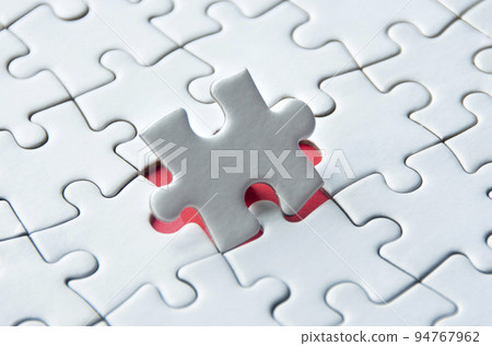 White jigsaw puzzle on red cover background with customizable space for text. Copy space and puzzle concept 94767962