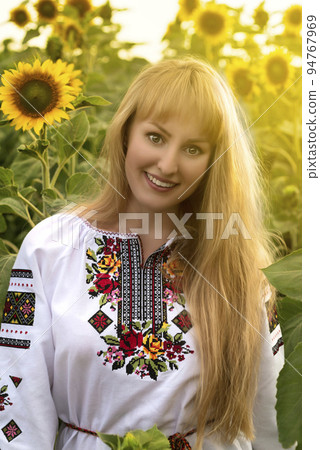 Attractive girl with long hair in Ukrainian vyshyvanka posing among the bales in the field 94767969