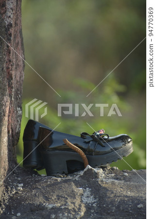 Young girl shoe over vintage stone wall-lost child concept Young girl shoe over vintage stone wall-lost child concept 94770369