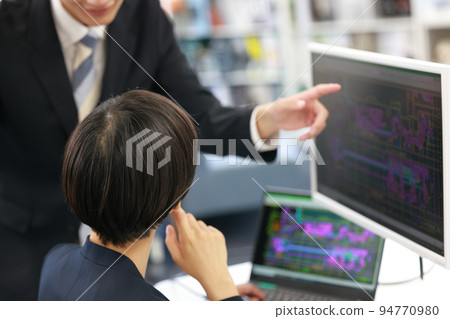 A female designer receiving a lecture on CAD operation from a senior employee_4 94770980