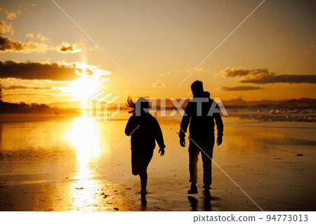Silhouette of a woman chasing a man in the sunset 94773013