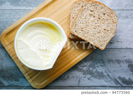fresh butter in a container with bread on white background  94773560