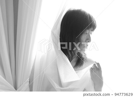 一個女人在晨光中沐浴時拿著窗簾的身影 一個女人在晨光中沐浴時拿著窗簾的身影 94773629