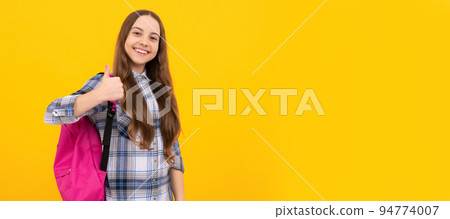 cheerful child in checkered shirt with backpack on yellow background. Portrait of schoolgirl student, studio banner header. School child face, copyspace. cheerful child in checkered shirt with backpack on yellow background. Portrait of schoolgirl student, studio banner header. School child face, copyspace. 94774007