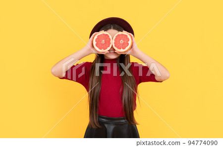 smiling kid behind grapefruit on yellow background, antioxidants smiling kid behind grapefruit on yellow background, antioxidants 94774090