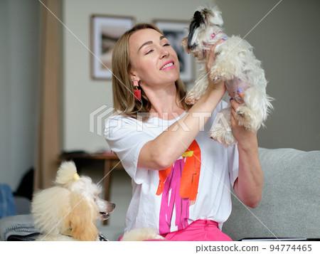 A woman lovingly looks at a beaver Yorkshire Terrier dog holding it in her hands 94774465