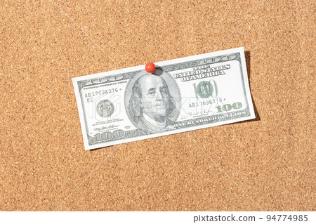 Fake one hundred dollar banknote pinned on cork board 94774985