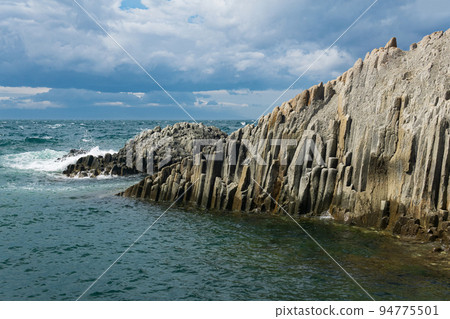 rocky seashore formed by columnar basalt against the surf, coastal landscape of the Kuril Islands rocky seashore formed by columnar basalt against the surf, coastal landscape of the Kuril Islands 94775501