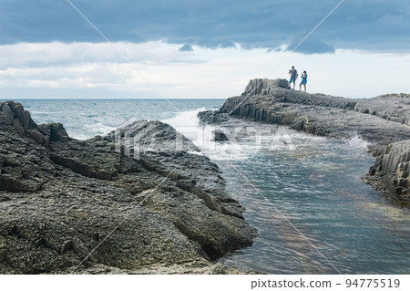 coastal seascape with beautiful columnar basalt rocks at low tide, tourists is seen in the distance in blur coastal seascape with beautiful columnar basalt rocks at low tide, tourists is seen in the distance in blur 94775519