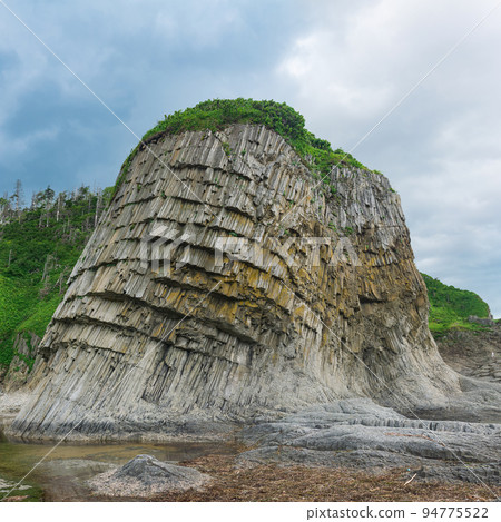 coastal landscape, beautiful columnar basalt cliff on the wooded coast of Kunashir island coastal landscape, beautiful columnar basalt cliff on the wooded coast of Kunashir island 94775522