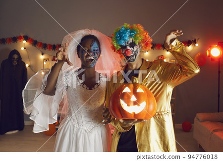 Two happy adult friends dressed in Halloween costumes of Dead Bride and Crazy Clown Two happy adult friends dressed in Halloween costumes of Dead Bride and Crazy Clown 94776018