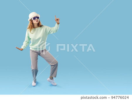 Funny happy young woman in fashionable outfit dancing on blue copy space background Funny happy young woman in fashionable outfit dancing on blue copy space background 94776024