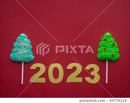 2023 and green, blue candies in the form of a Christmas tree on a red background 2023 and green, blue candies in the form of a Christmas tree on a red background 94776226