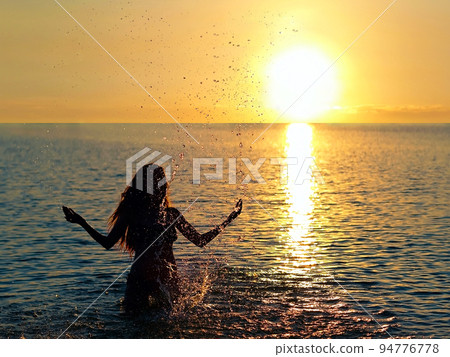 girl standing in the lake water in the rays of the setting sun 94776778