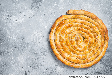 Baked homemade traditional Greek cheese pie on kitchen table. Gray background. Top view. Copy space 94777209