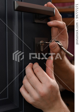 Installation of a door lock, a carpenter installs a door lock in a door, work close-up. 94777271