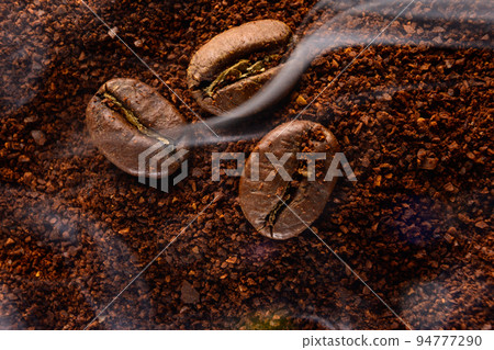 ground coffee and three beans in a light smoke. ground coffee and three beans in a light smoke. 94777290