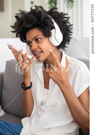 Cheerful woman in headphones recording voice message 94777339