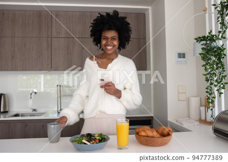 Portrait of young woman working from home standing in kitchen 94777389