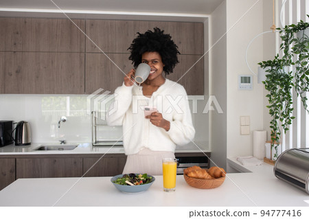 Portrait of young woman working from home drinking coffee Portrait of young woman working from home drinking coffee 94777416