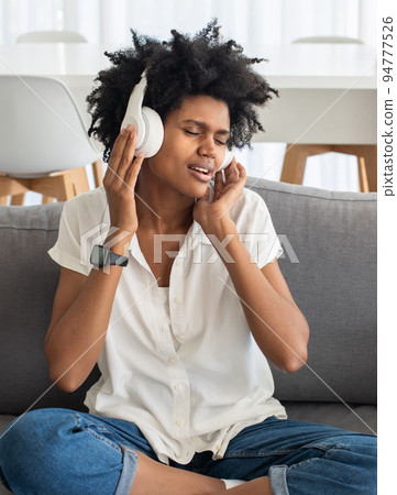 Happy woman listening to music on headphones at home 94777526