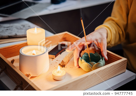Self care, mental health. Young woman sitting near table with lights candles, Aroma Sticks, enjoy meditation at home. No stress, healthy habit, mindfulness lifestyle, anxiety relief concept 94777745