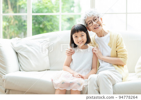 Senior woman and granddaughter relaxing in the living room 94778264