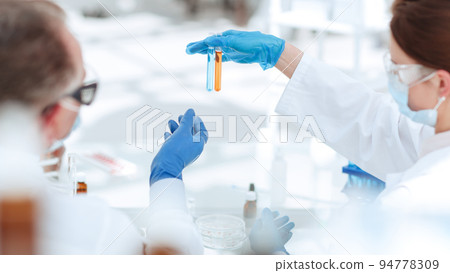 rear view . Microbiology scientists discussing the liquid in test tubes. rear view . Microbiology scientists discussing the liquid in test tubes. 94778309