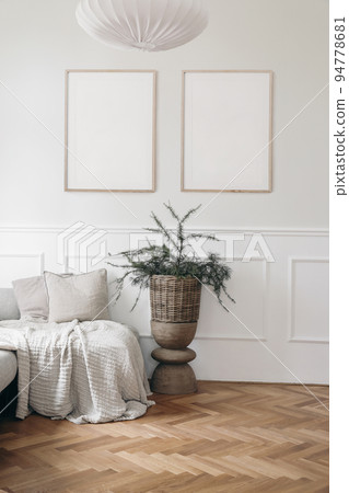 Christmas interior. Two blank vertical wooden picture frames mockups. White wall background.. Bed, sofa with linen cushions, blanket. Larch, pine tree branches in wicker basket, wooden coffee table. Christmas interior. Two blank vertical wooden picture frames mockups. White wall background.. Bed, sofa with linen cushions, blanket. Larch, pine tree branches in wicker basket, wooden coffee table. 94778681