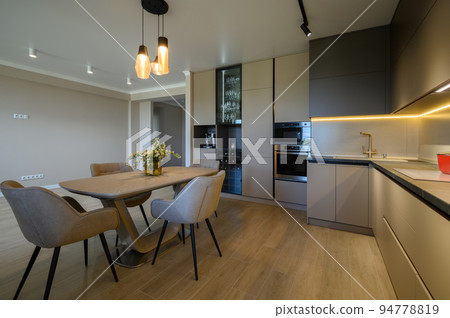 Large modern grey luxurious kitchen with dining table in studio apartment Large modern grey luxurious kitchen with dining table in studio apartment 94778819