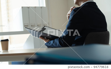 Businessman worried about looking at documents 94779618