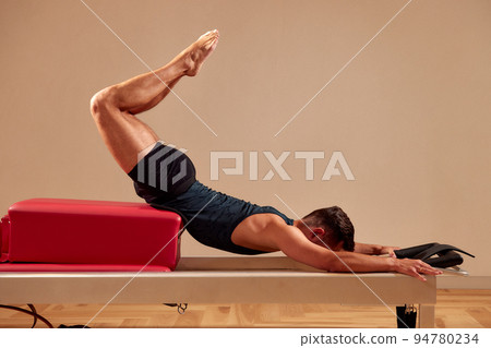 Pilates reformer workout exercises man at gym indoor 94780234