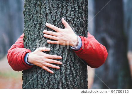 Tree hugger, hands embracing old tree trunk in fall, woman meditating in autumn park Tree hugger, hands embracing old tree trunk in fall, woman meditating in autumn park 94780515