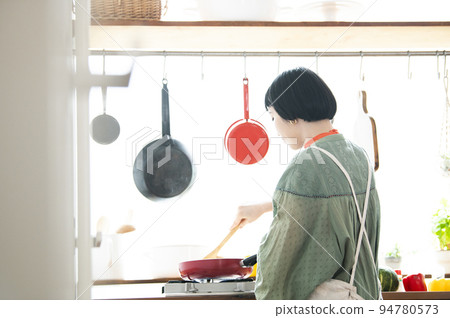 Young woman cooking, back view 94780573